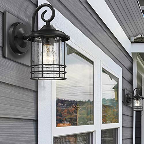 Outdoor wall light fixture on a gray house with windows.